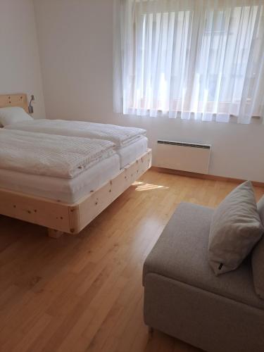 1 dormitorio con 2 camas, sofá y ventana en Chasa Azura en Scuol