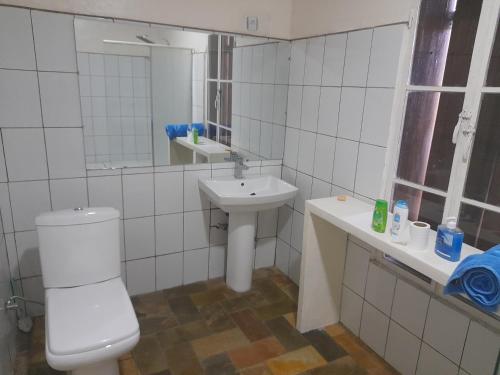 a white bathroom with a toilet and a sink at Rwanda African Art Museum in Nyabisindu