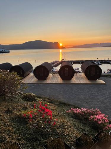 a sunset over a body of water with a group of tents at Smaken av Ryfylke Event AS overnatting, Bygningen drives ikke som hotell in Hjelmeland