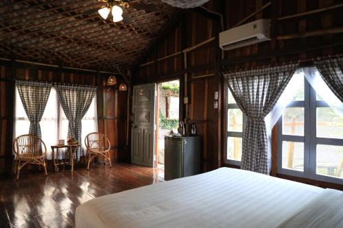 sypialnia z łóżkiem, 2 krzesłami i oknami w obiekcie Vamxang Rustic Home w mieście Cần Thơ
