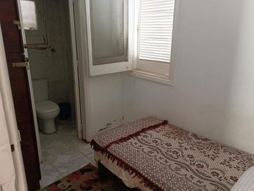 a bathroom with a bed and a window and a toilet at 3 غرف و صاله جرين بيتش الساحل الشمالي للعائلات فقط in El Alamein