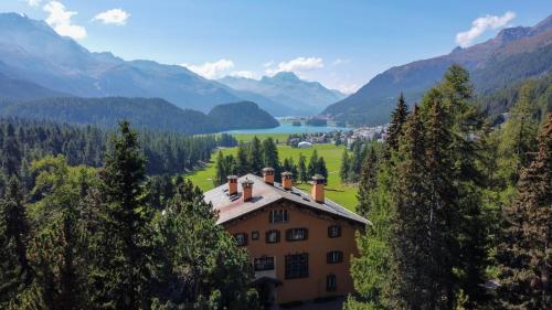 a house in a valley with a lake and mountains at Hotel Chesa Spuondas in St. Moritz