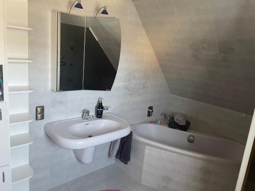 a white bathroom with a sink and a bath tub at Naturpark Ferienwohnung mit Wintergarten in Spraitbach