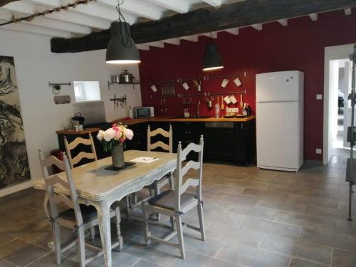 une cuisine avec une table avec des chaises et un réfrigérateur dans l'établissement Jolie maison en pierre proche centre-ville, à Cherbourg en Cotentin