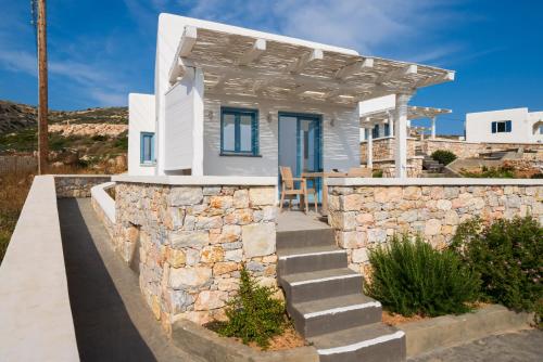 una pequeña casa blanca con una pared de piedra en Camvillia Donoussa Village Suites, en Donoussa