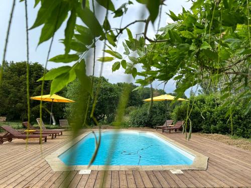 - une piscine avec des chaises et des parasols sur une terrasse en bois dans l'établissement Le Sarment, à Grézillac