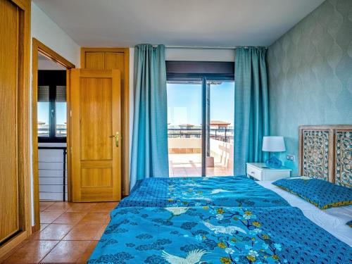 a bedroom with a blue bed with a view of the ocean at Villa Origo Mare 1236 in Majanicho in Lajares