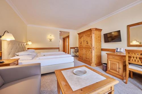 a bedroom with a bed and a couch and a table at Hotel Zugspitze in Garmisch-Partenkirchen