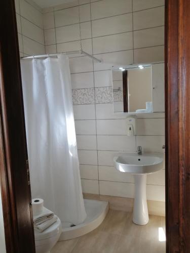baño con cortina de ducha blanca y lavamanos en OASIS APARTMENTS en Livadia