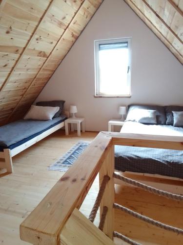 a loft bedroom with two beds and a table at Letniskowiec Kownatki in Siemienowo