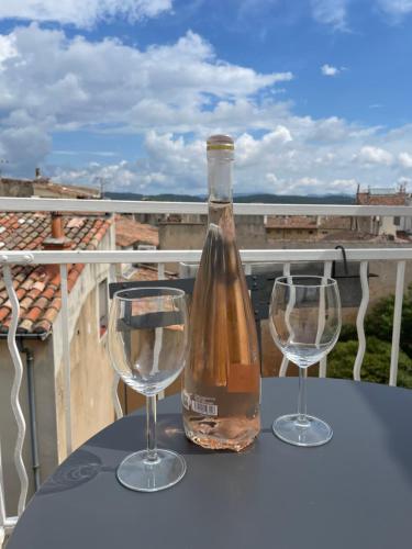 une bouteille de vin et deux verres à vin sur une table dans l'établissement 2 pièces climatisé en duplex avec terrasse, à Aix-en-Provence