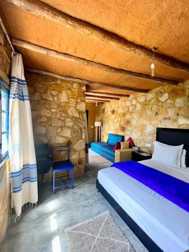 a bedroom with a bed and a stone wall at Dmina House in Asilah