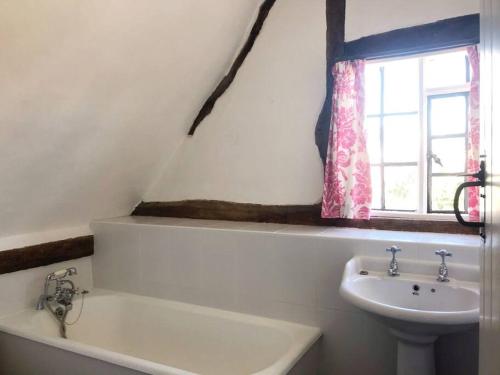 a bathroom with a sink and a bath tub and a window at Cider Mill Cottage in Alderton