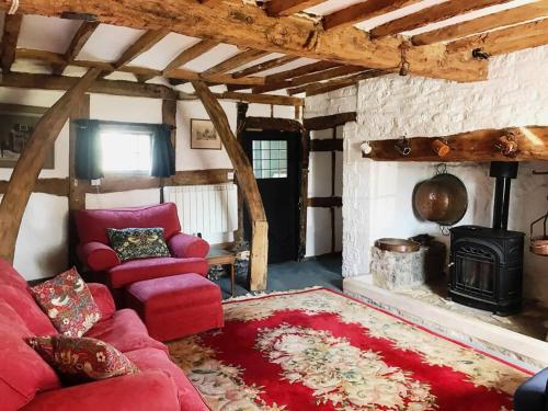 a living room with a red couch and a stove at Cider Mill Cottage in Alderton