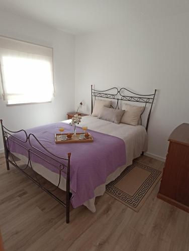 Casa da avó Zita في بومبال: غرفة نوم بسرير كبير مع بطانية ارجوانية