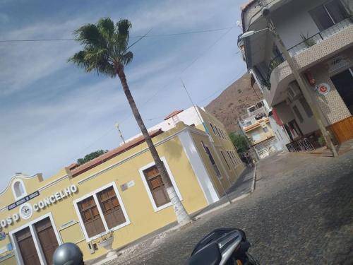 a palm tree in front of a yellow building at Old house in Tarrafal