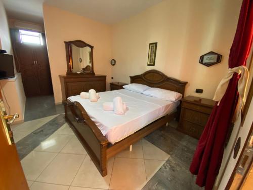 Schlafzimmer mit einem Bett mit weißer Bettwäsche und einem Spiegel in der Unterkunft Hotel W Bush Square in Fushë-Krujë