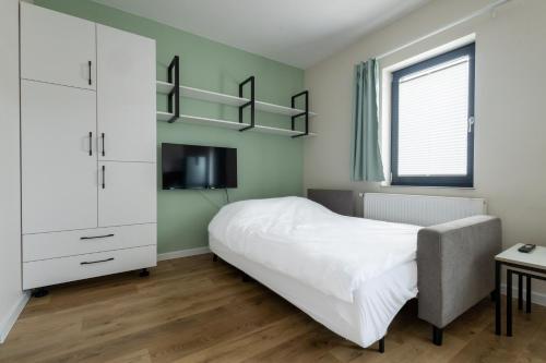 Schlafzimmer mit einem weißen Bett und einem TV in der Unterkunft Brzeska 22 in Łódź