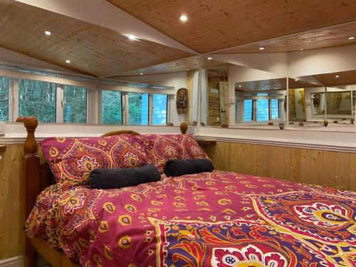 a bedroom with a large bed in a room with windows at Cuckoo Cabin, Tyn Y Cwm in Scyborycoed
