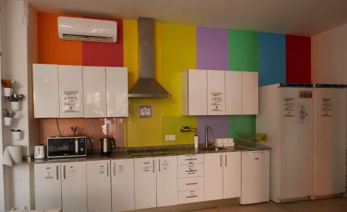 a kitchen with white cabinets and a colorful wall at Palma Port Hostel - Albergue Juvenil in Palma de Mallorca