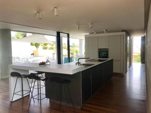 une cuisine avec un grand îlot avec un évier et des tabourets dans l'établissement Contemporaine, à Bandol