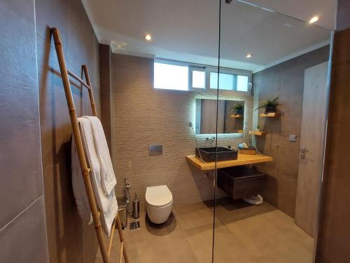 a bathroom with a shower and a toilet and a sink at New minimal apartment,10' from Athens airport in Spáta