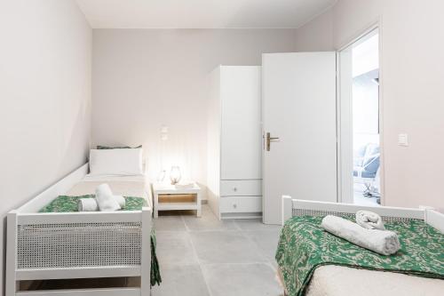 a white bedroom with two beds and a window at Aroma Accommodations in Kivérion