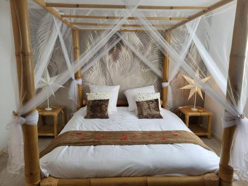 ein Schlafzimmer mit einem Himmelbett mit weißer Bettwäsche und Kissen in der Unterkunft Une petite maison seulement pour 2 