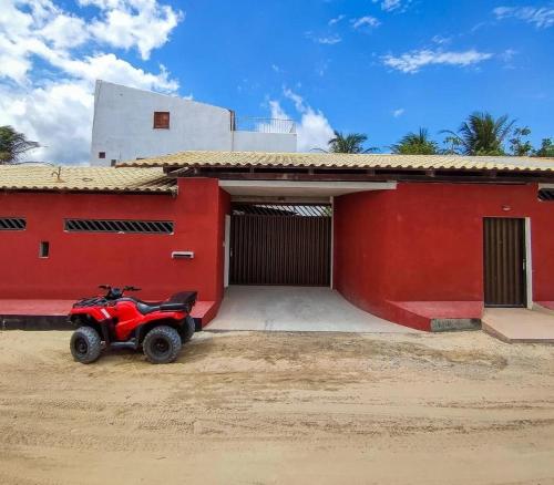a red building with a atv parked in front of it at Freddyssimo Preá in Prea