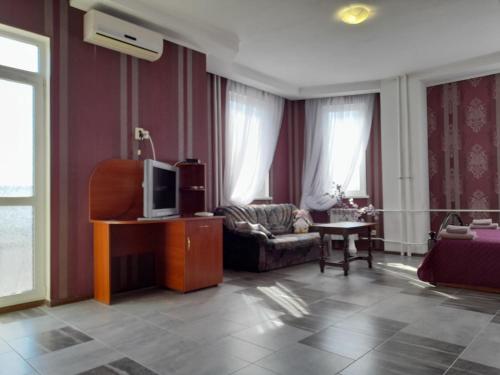 ein Wohnzimmer mit einem Sofa und einem TV in der Unterkunft SunLake Hotel Osokorki in Kiew