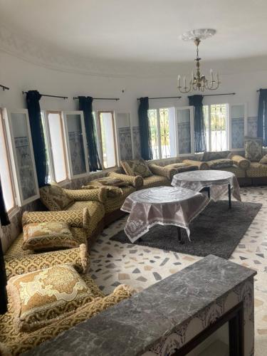 a living room with couches and tables and windows at Villa Bellouti in Tangier