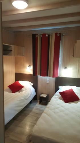 una camera d'albergo con due letti con cuscini rossi di Chalet nature proche lac et à 20 mn des plages en Vendée a La Chapelle-Hermier