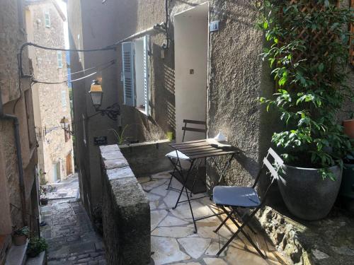 an alley with a table and chairs and a potted plant at Maisonnette au cœur du village in Le Bar-sur-Loup