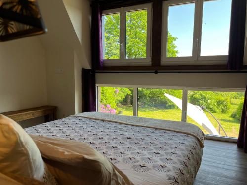 sypialnia z łóżkiem i dużym oknem w obiekcie Maison d'hôte avec sauna et jacuzzi à la campagne w mieście Les Portes du Coglais