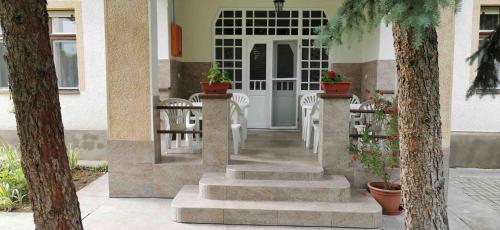 a porch with white chairs and a white door at István Apartman in Hajdúszoboszló