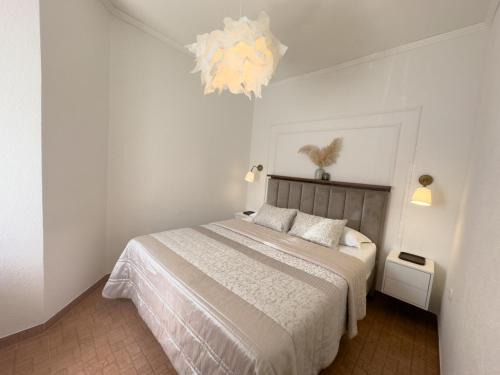 - une chambre blanche avec un lit et un lustre dans l'établissement Apartments Melita, à Podstrana
