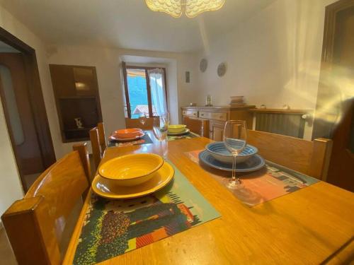 un tavolo in legno con piatti e un bicchiere di vino sopra di Casa vacanze il pettirosso. a Pisogne