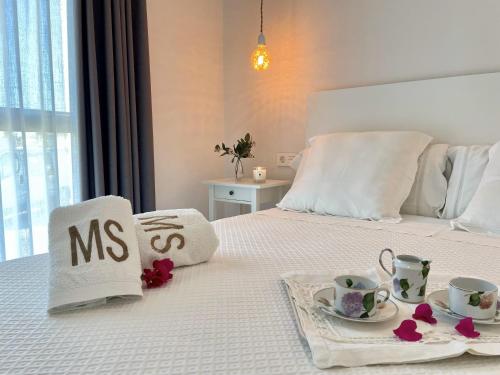a white bed with two cups and saucers on it at Apartamentos MadreSelva in Fernán Pérez