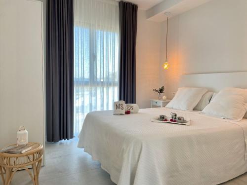 a white bed in a room with a large window at Apartamentos MadreSelva in Fernán Pérez