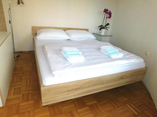 a bed with white sheets and two towels on it at Apartment Mateo in Maribor
