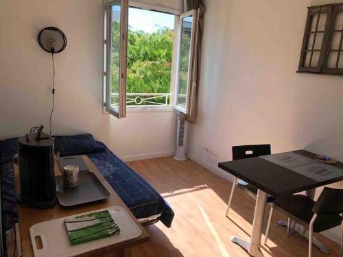 Cette petite chambre comprend une table, un lit et une fenêtre. dans l'établissement Charmant Studio climatisé Aix en Provence - parking gratuit, à Aix-en-Provence