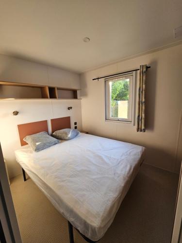 1 dormitorio con 1 cama blanca grande y ventana en Camping Le Dolium, en Laudun