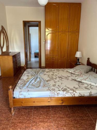 een slaapkamer met een groot bed en een houten kast bij Relax Apartment in Sarandë