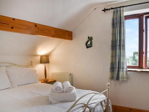 1 dormitorio con 1 cama con toallas en Honeysuckle Cottage, en Bishopston