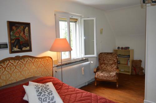una camera con un letto e una sedia e una finestra di Chez Thérèse et Marguerite 