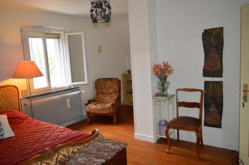 a bedroom with a bed and a chair and a window at Chez Thérèse et Marguerite in Kindwiller