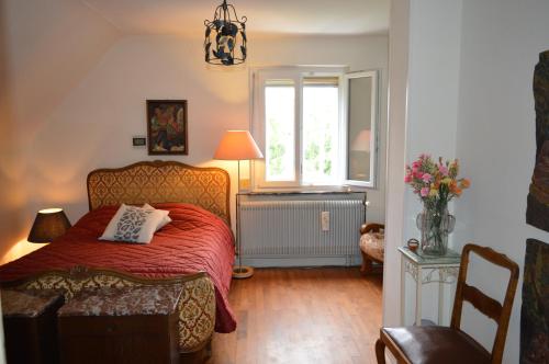a bedroom with a bed with a red blanket and a window at Chez Thérèse et Marguerite in Kindwiller