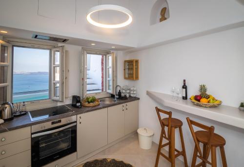 a kitchen with a sink and a counter with chairs at Oia Mare Villas in Oia