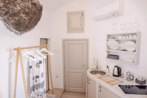 a small white kitchen with a sink and a sink at Oia Mare Villas in Oia