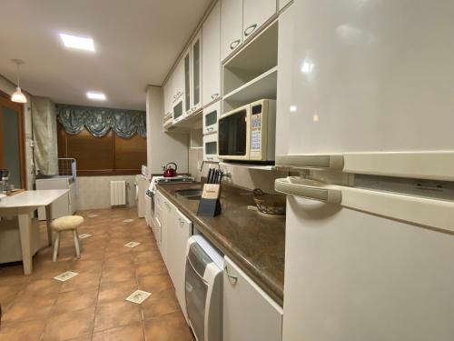 eine Küche mit weißen Schränken und einer Arbeitsplatte in der Unterkunft LUXUOSO APT ALMERIS PECCIN no Centro de GRAMADO in Gramado